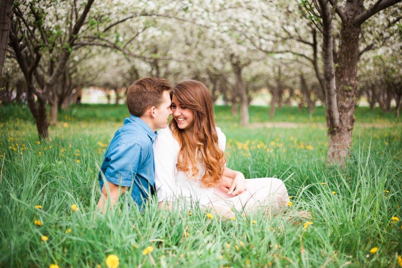 A couple smiling together in a green spring orchard