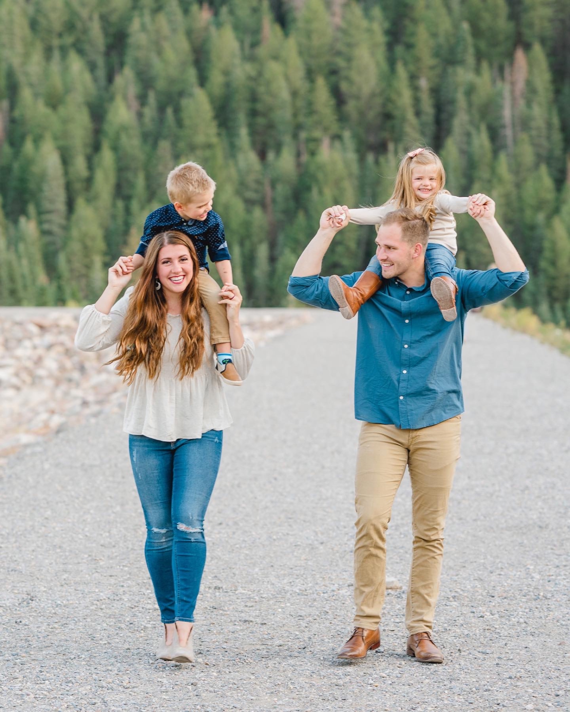 Parents carrying their children on their shoulders on a forest road