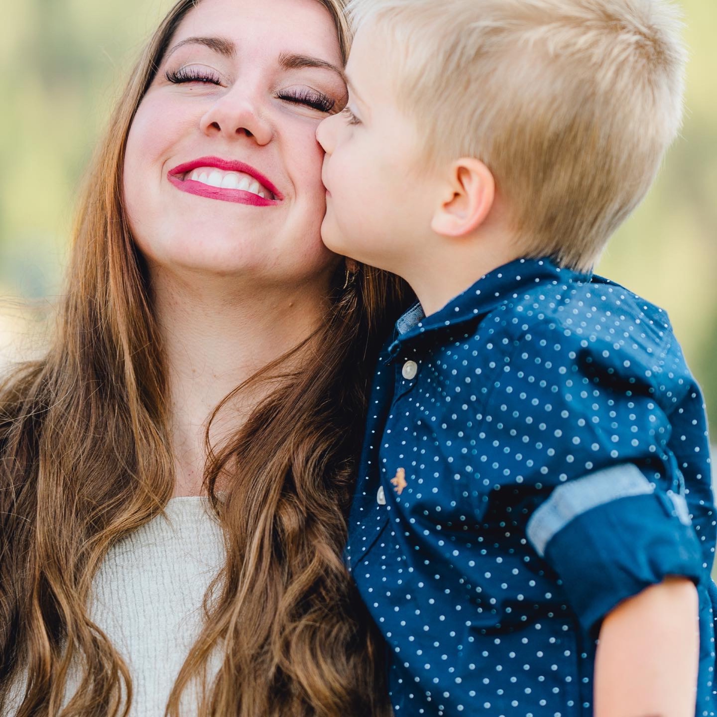 A little boy kissing his smiling mother on the cheek